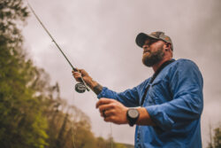 Medium shot of man casting a line in the water.
