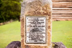 Sign embedded in stone marking the site of the first pioneer cabin on the watershed of Duck Creek.