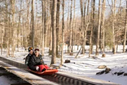 A couple riding a sled on the sled run at Blackwater Falls State Park.