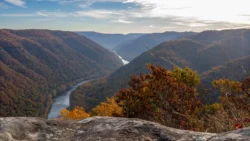 Wide shot of the New River Gorge National Park from a scenic overlook showing mountains and the New River during the fall.