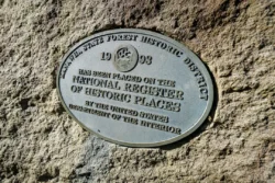 A National Register of Historic Places marker for the Kanwha State Forest Historic District atop a large boulder.