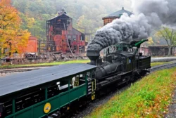 Locomotive traveling on the railroad and passing the original lumber mill in Cass during the fall.