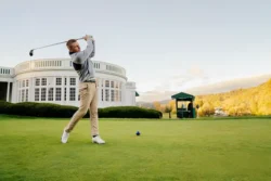Young man amid his golfer's swing on a course at the Greenbrier Resort.