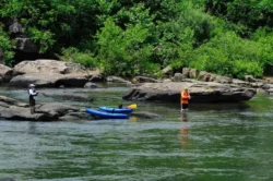 Two men park their kayaks amid shallow water in Tygart Lake for some summertime fishing.