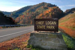 Chief Logan State Park road sign with mountainous terrain in the background during the fall.