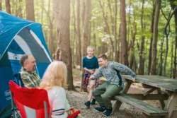 Family of four relaxing by the tent on Tomlinson Run State Park's campground during the fall.