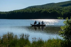 Three guests fishing amid Moncove Lake during the summer.