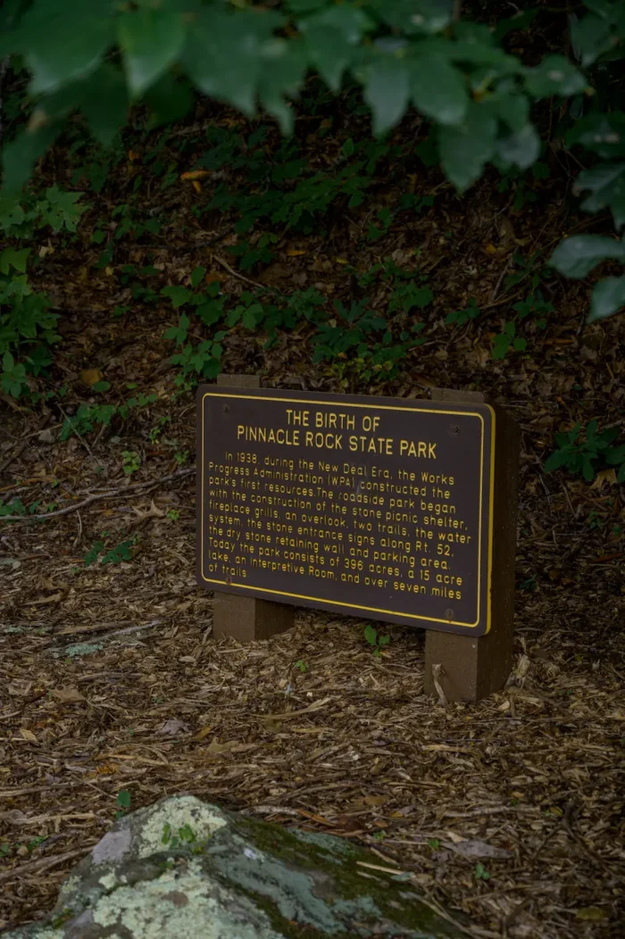 Sign marker amid Pinnacle Rock State Park with a history overview.