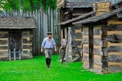A costumed interpreter walking through Pricketts Fort State Park in the summertime.