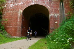 Cyclist riding his bike through a tunnel on the North Bend Rail Trail during the summer.