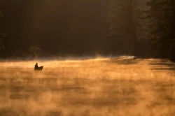 Fishing in a boat on Seneca Lake at dawn with a subtle fog over the water.