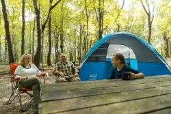 Family of three relaxing by their tent on the campground of Tomlinson Run State Park in the spring.