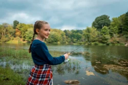 Young girl enjoying some lakeside fishing during the fall in Tomlinson Run State Park.