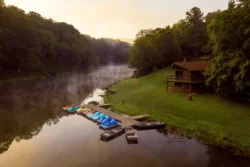 Tomlinson Run Lake amid summertime greenery with blue skies and a subtle fog.