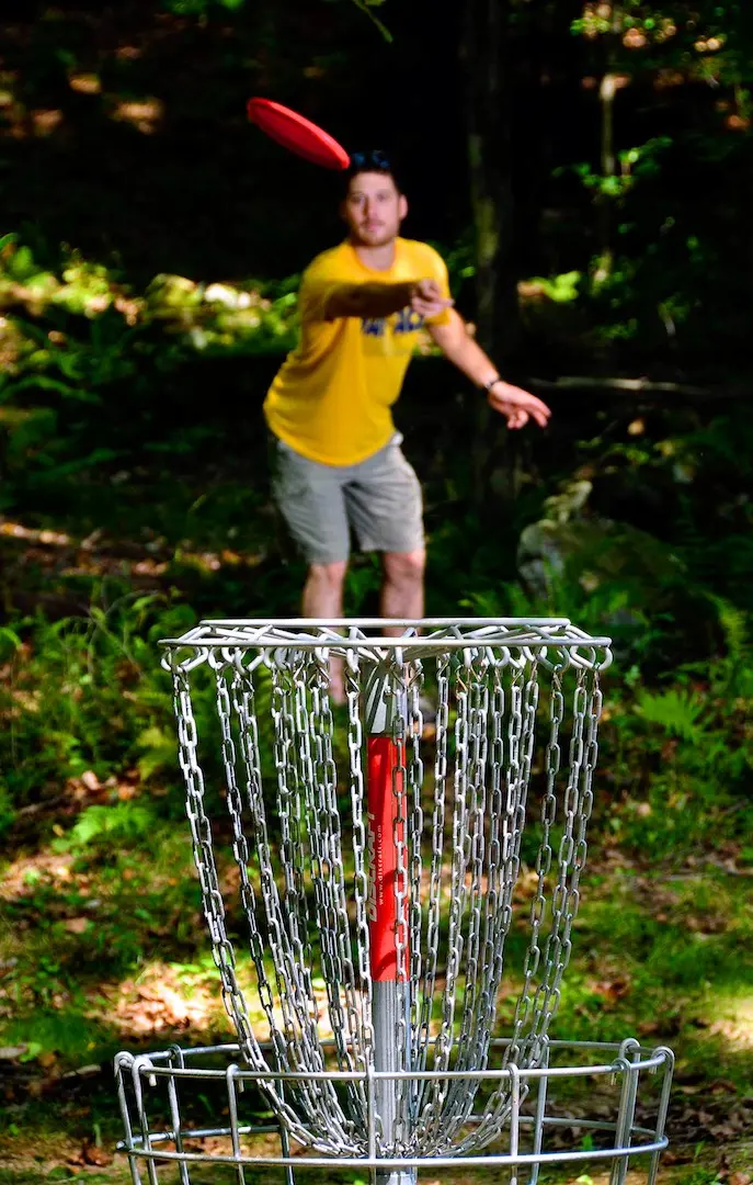 Visitor enjoying the disc golf course on a summer evening in Tomlinson Run State Park.