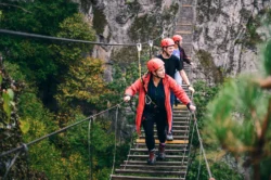 A group of climbers walking across a bridge with NROCKS during the summer.