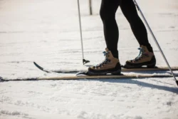 A skiers legs with skis on some snow