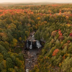 A distant aerial shot of Blackwater Falls among the trees just starting to turn for autumn