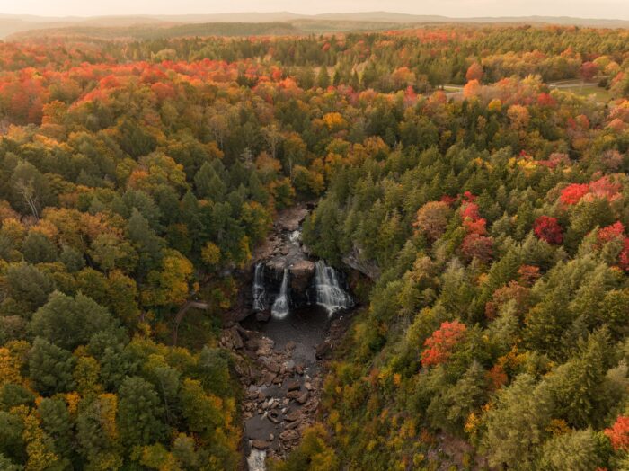 A distant aerial shot of Blackwater Falls among the trees just starting to turn for autumn