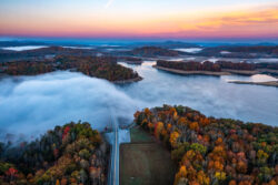 An aerial view of Summersville Lake in the fall with part of the lake covered by fog
