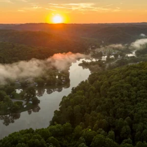 Aerial view of lake and forest at sunset with low fog at Beech Fork State Park