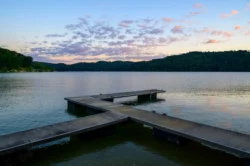 Dock extending into Tygart Lake at sunset with calm water and forested hills