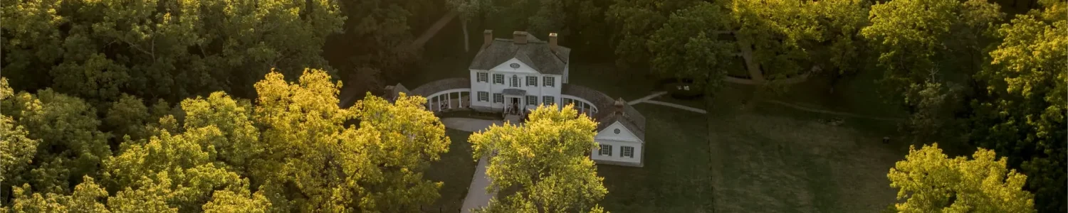 Aerial view of Blennerhassett Island Historical State Park mansion surrounded by forest and river at sunset